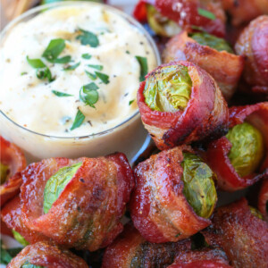 brussels sprouts wrapped in bacon on plate with sauce