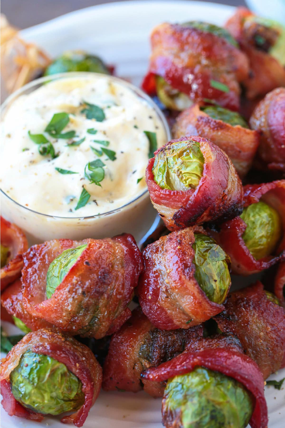 brussels sprouts wrapped in bacon on plate with sauce