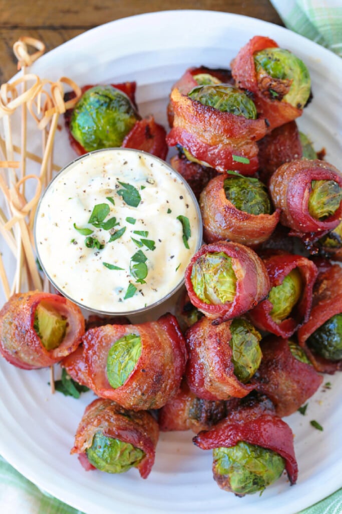 bacon wrapped brussels sprouts on white plate with sauce