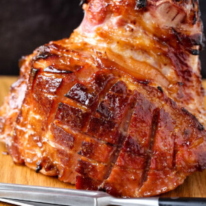 baked ham resting on board with carving knife