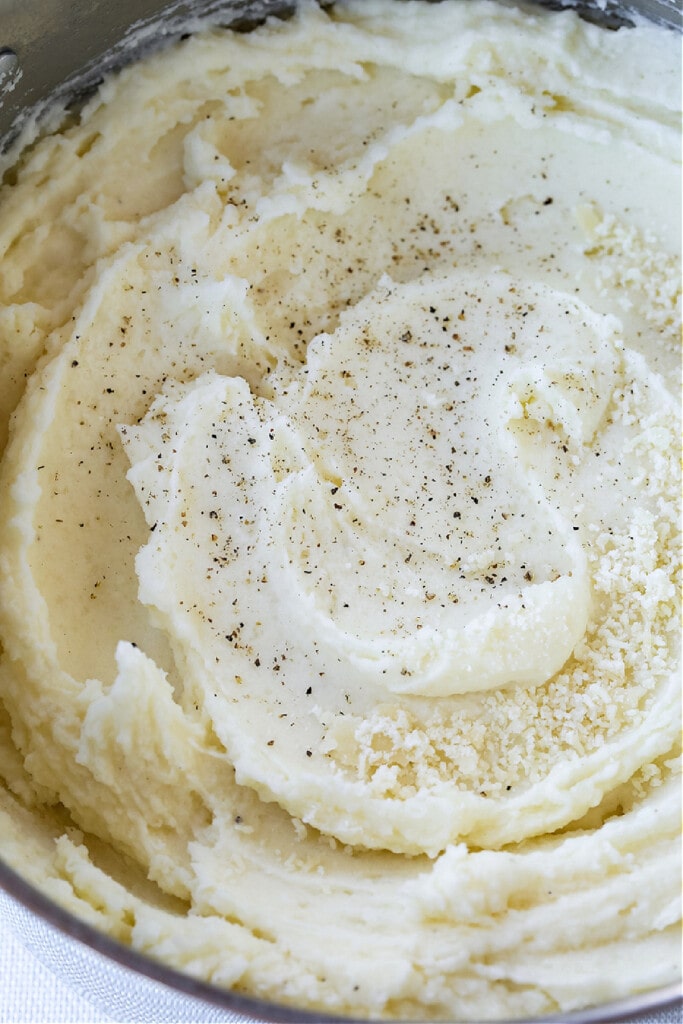 mashed potatoes in bowl with pepper and parmesan cheese