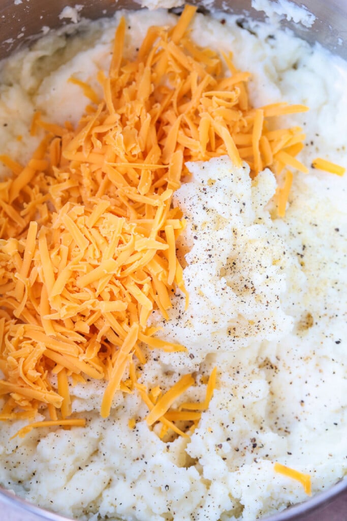 mashed potatoes in bowl with shredded cheddar cheese