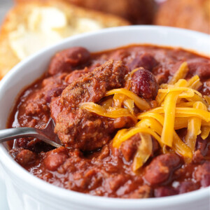 spoon in bowl of beef chili with cheese