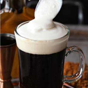 whipped cream being spooned on top of Irish coffee