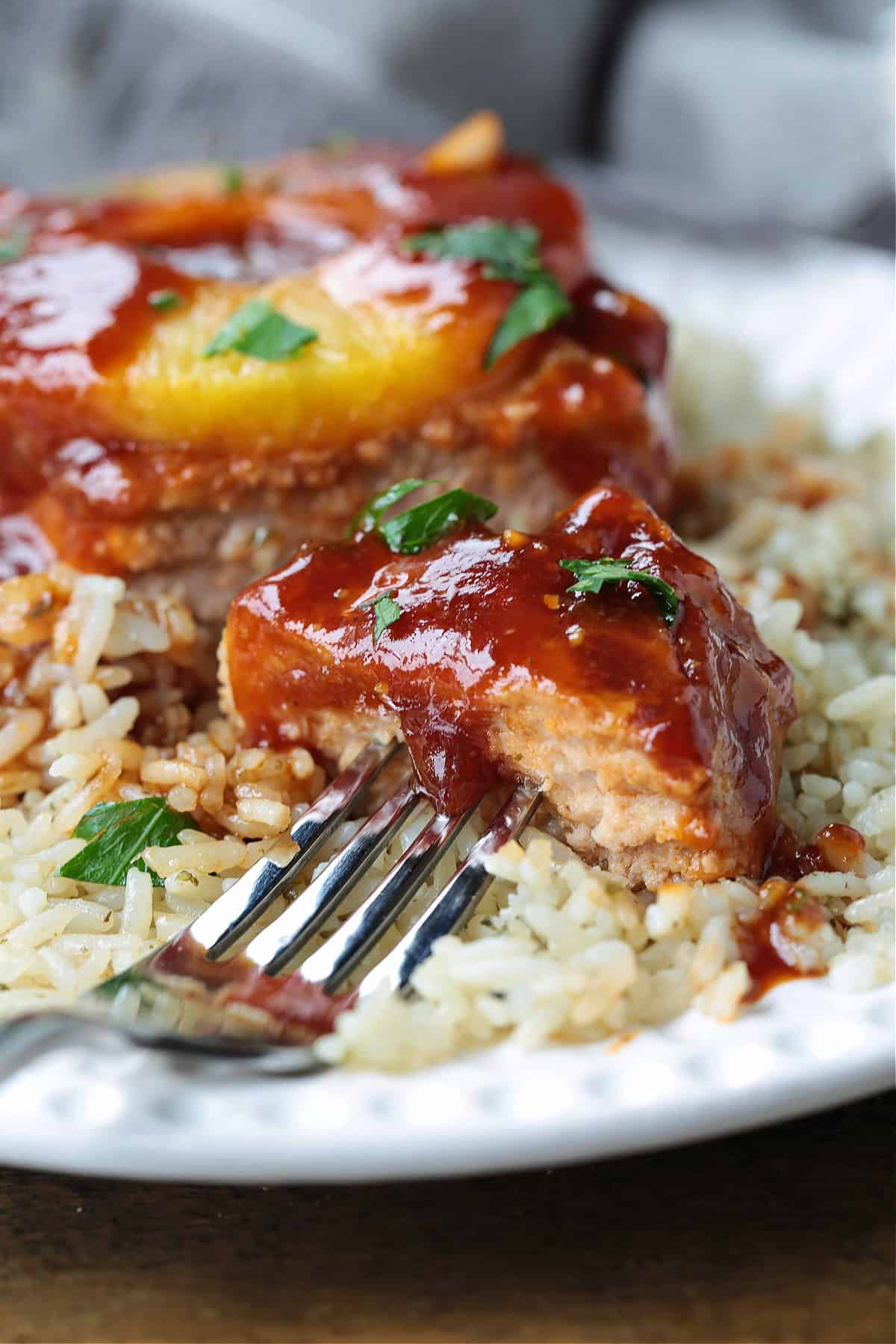 fork with bite of pork chop with sauce dripping down