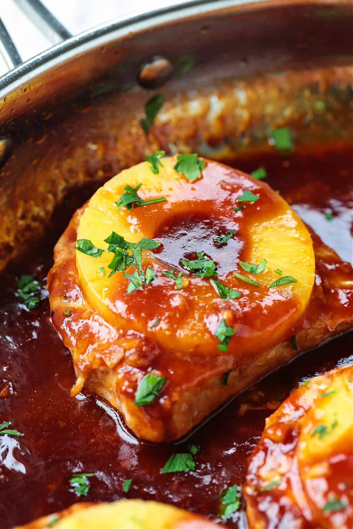 pork chop topped with sauce and pineapple in skillet