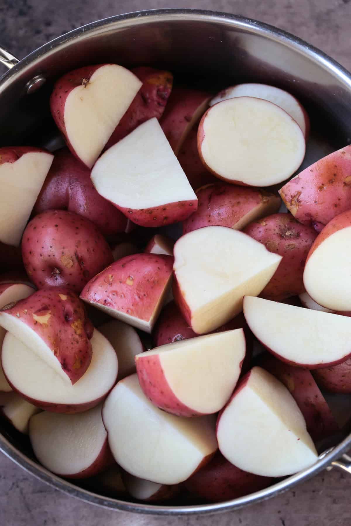 red potatoes cut in half in a pot