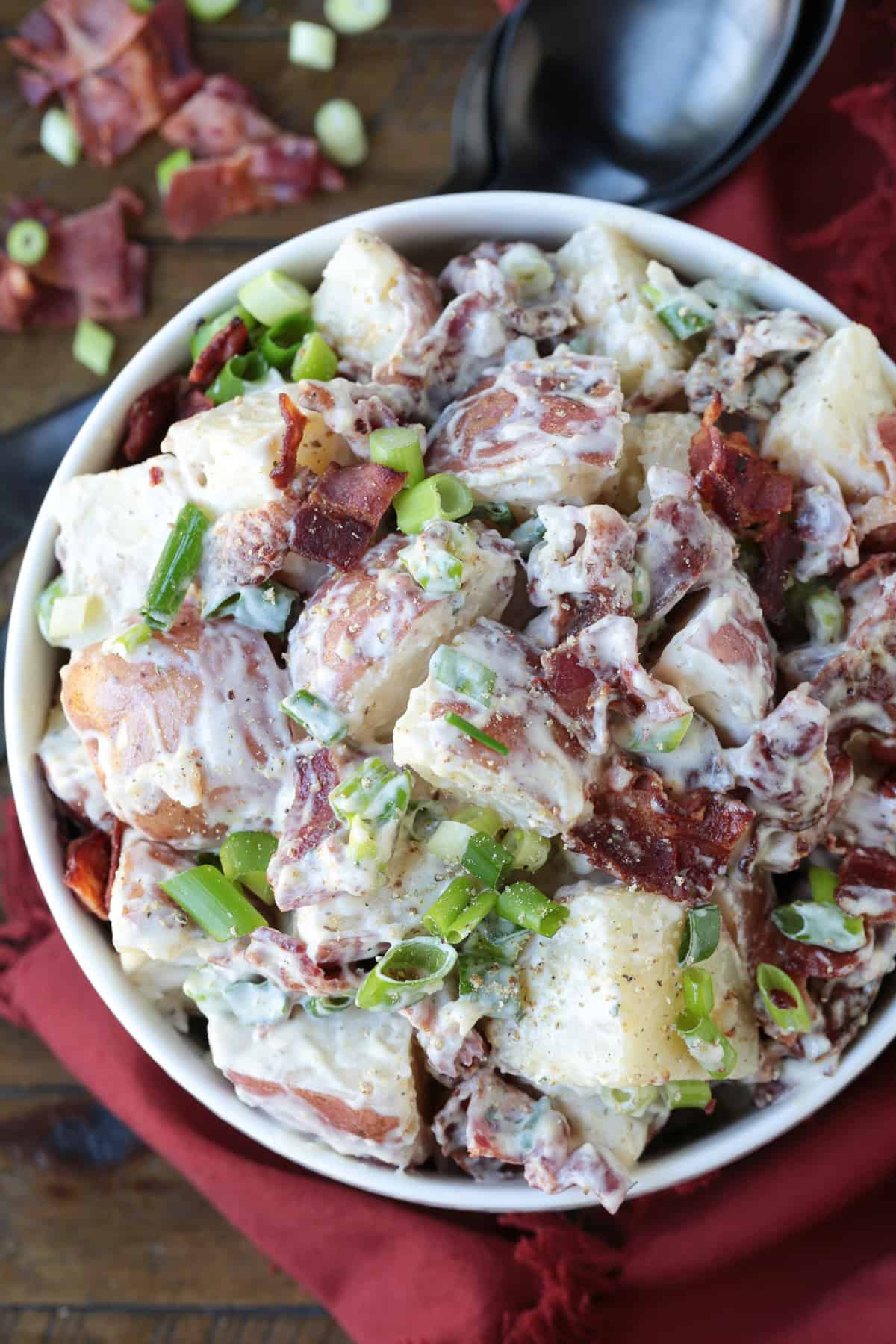 potato salad with bacon and scallions in white bowl