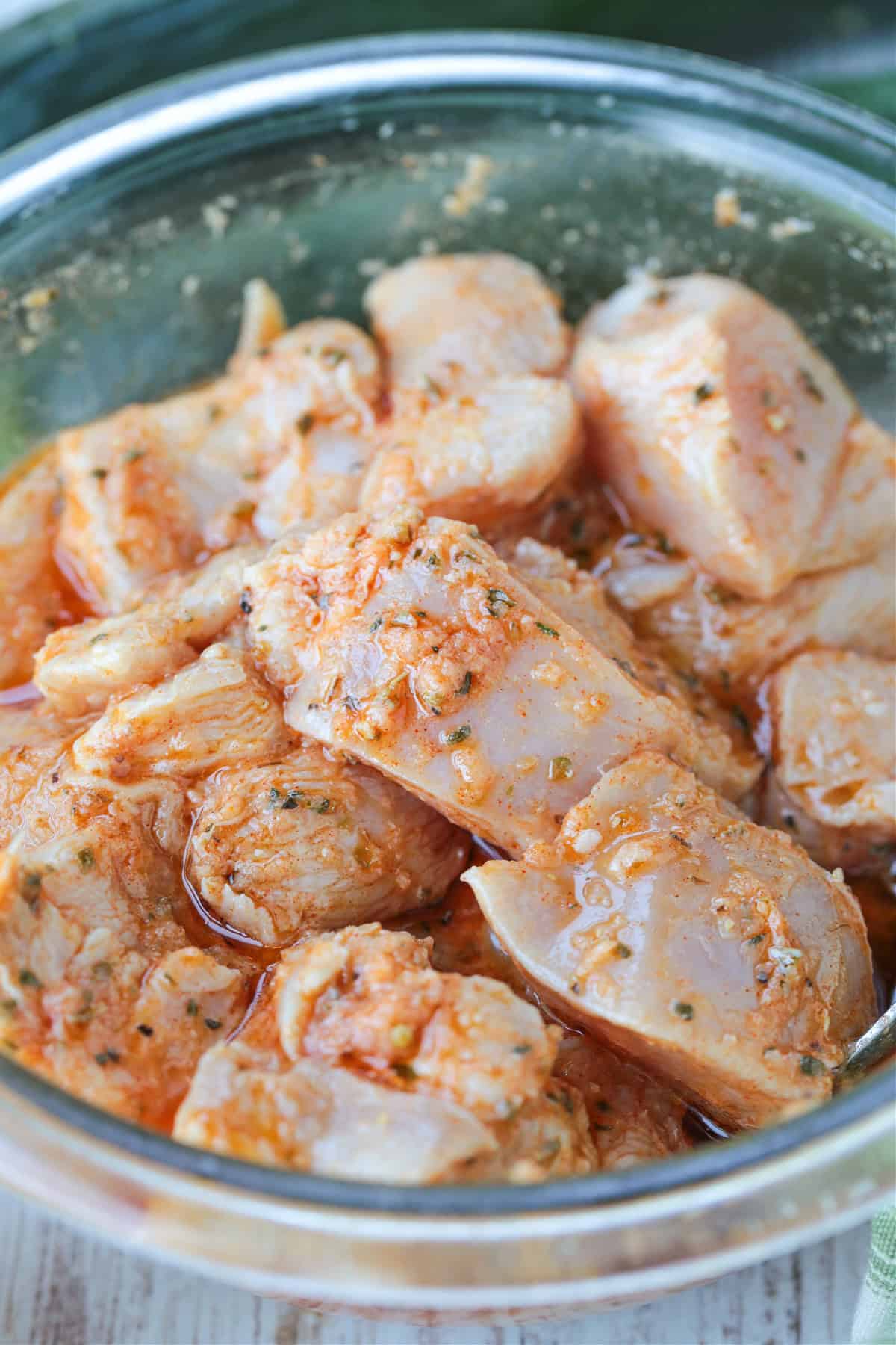 cubed chicken marinating in a glass bowl