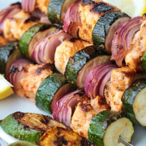 chicken kabobs with zucchini and red onion stacked on platter