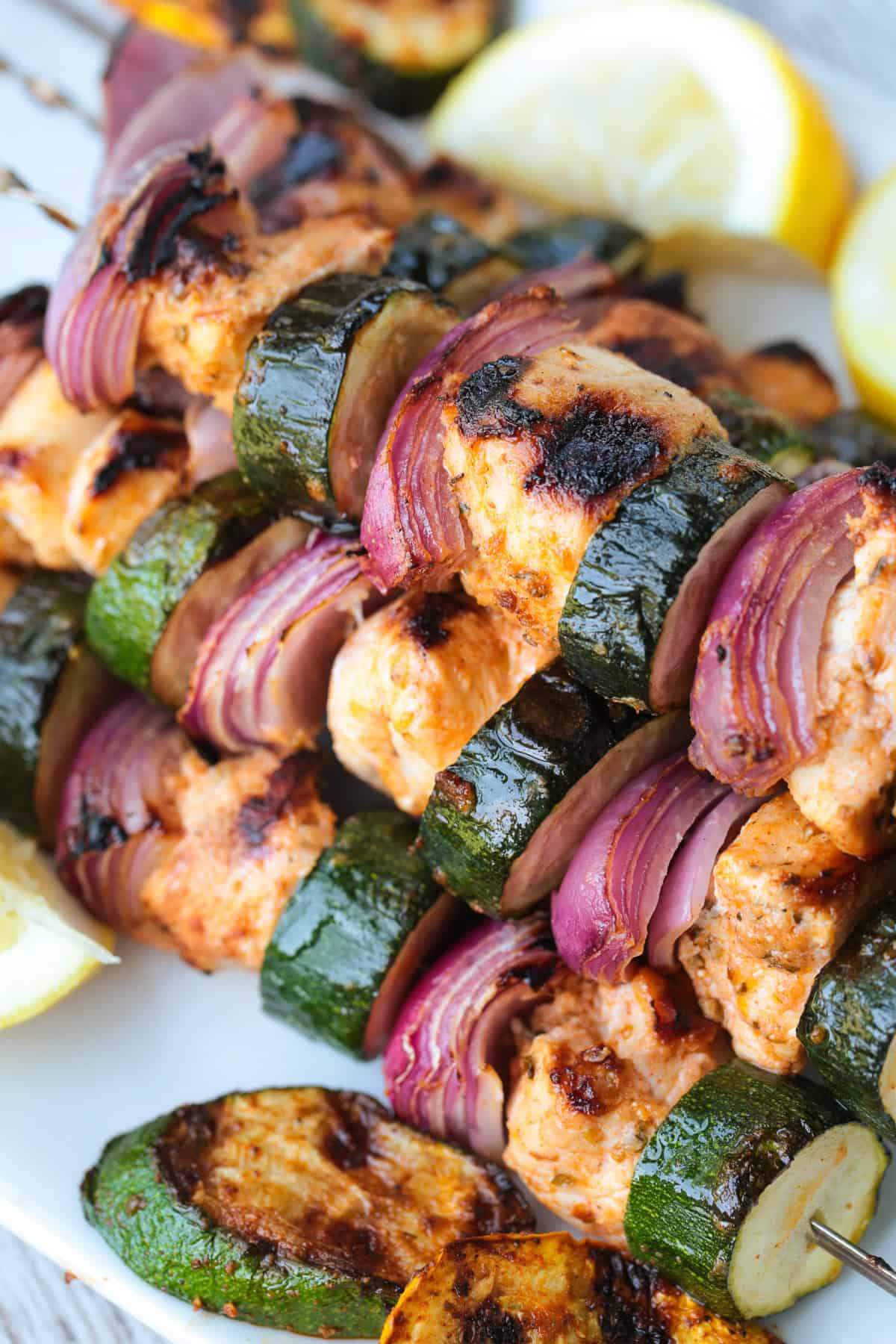 greek marinated chicken kabobs with vegetables stacked on plate