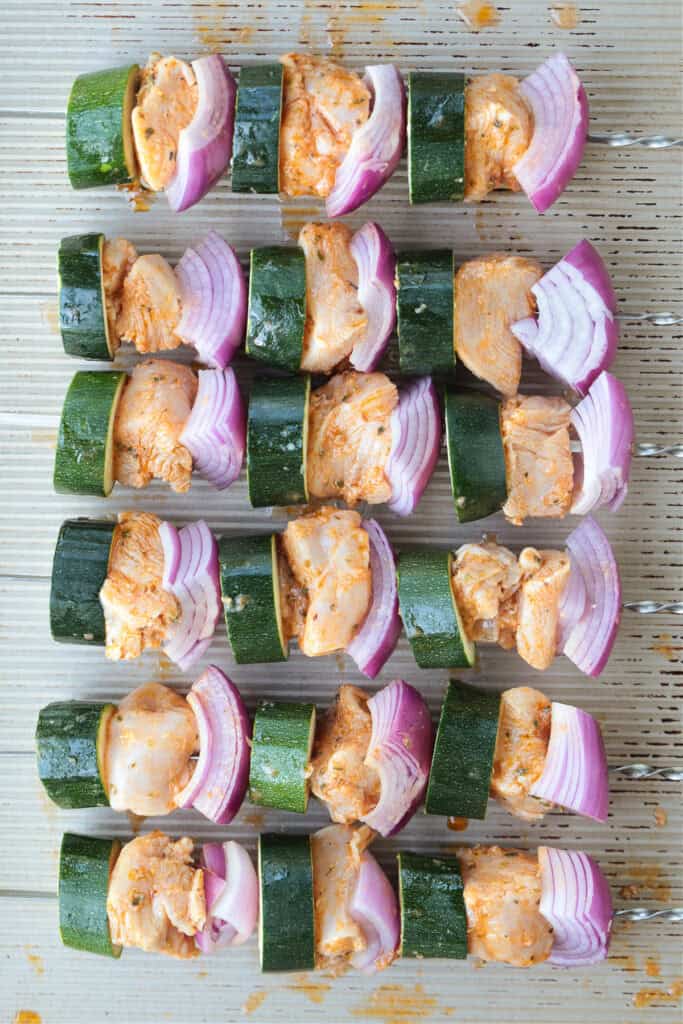 raw chicken skewers on baking sheet