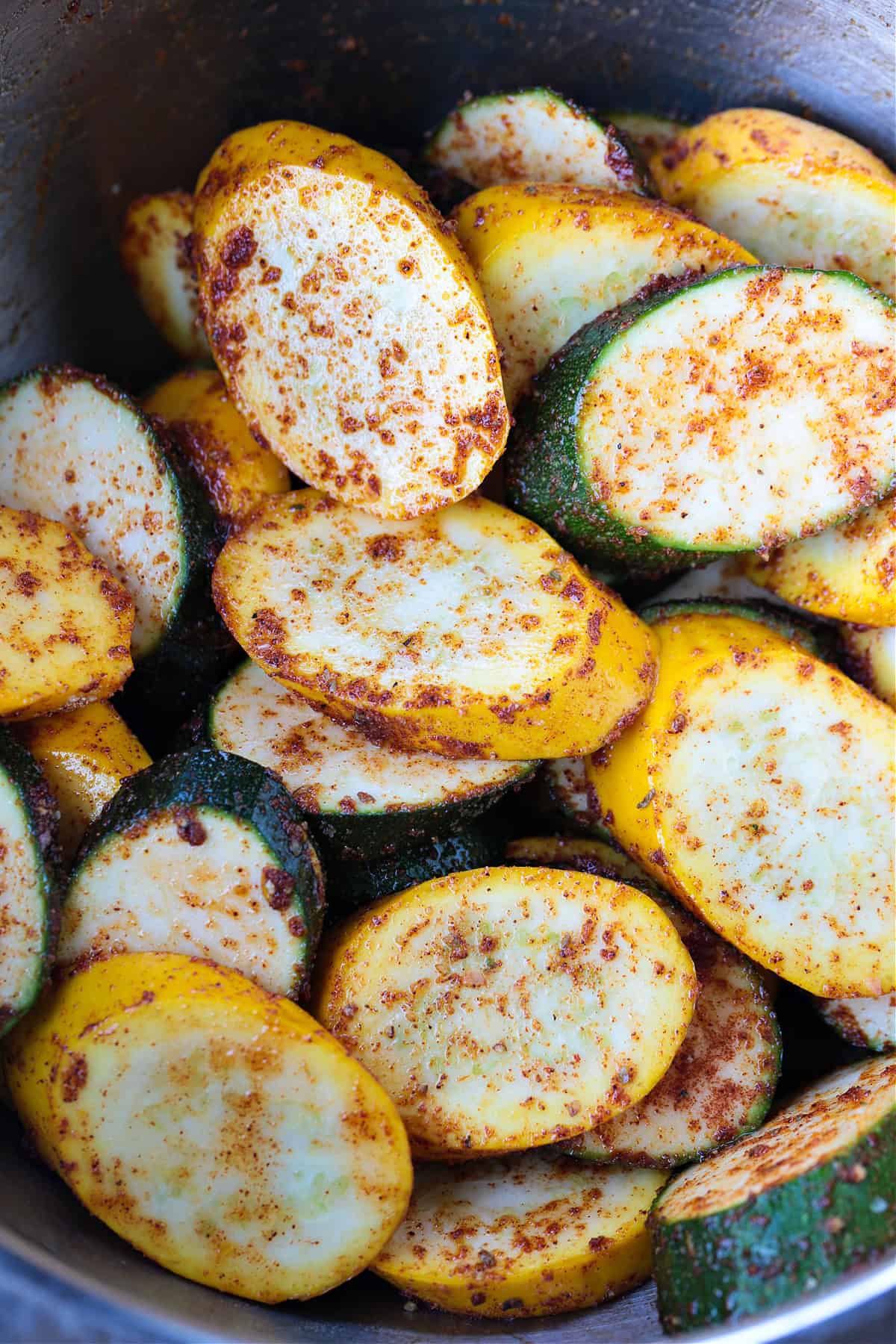 thick slices of zucchini and squash tossed with seasoning in bowl