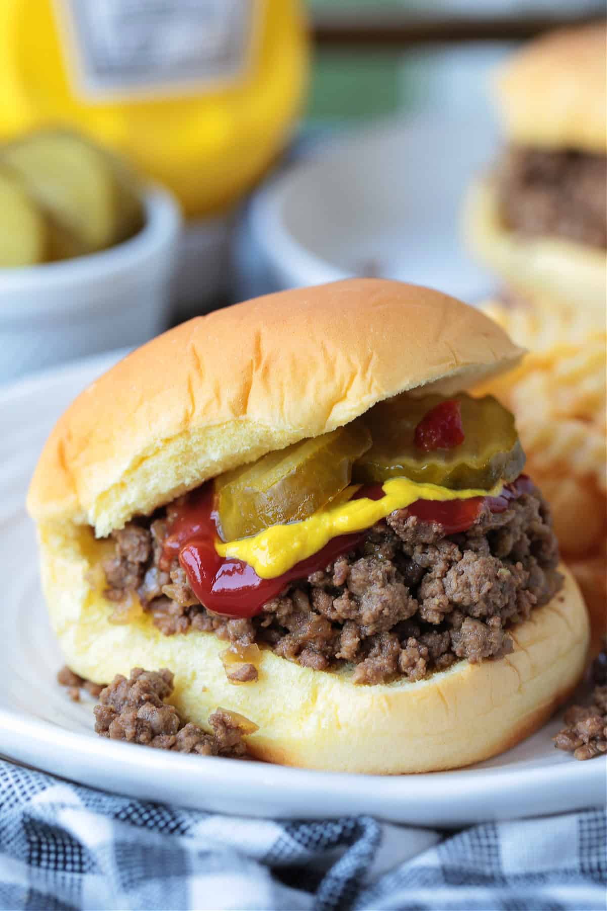 loose meat sandwich on bun with pickles, ketchup and mustard