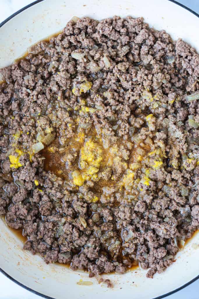 ground beef in a skillet with beef broth and mustard