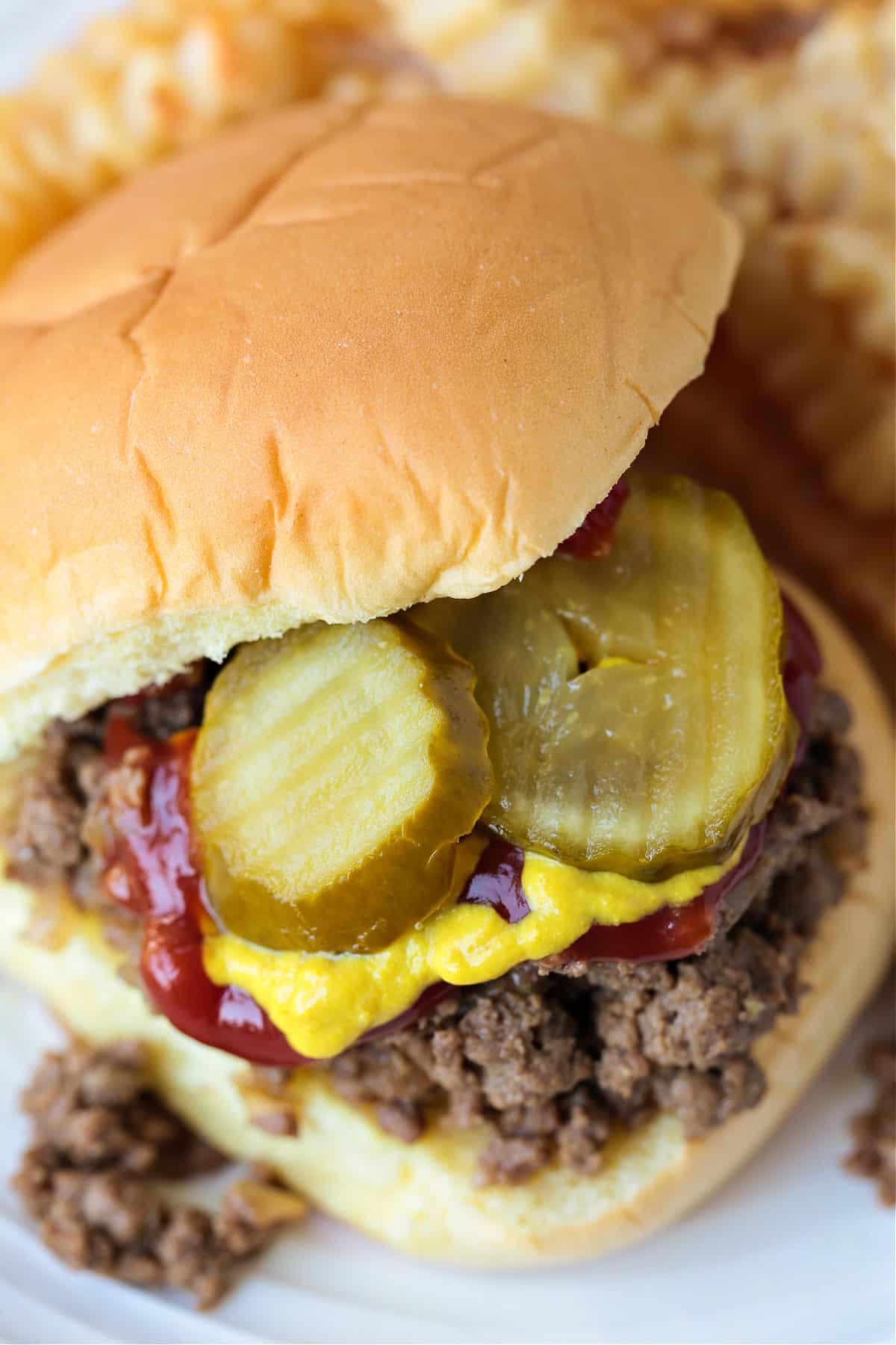 maid rite sandwich topped with mustard, ketchup and pickles