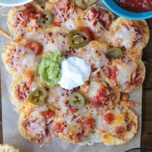 nachos on parchment with toppings on the side