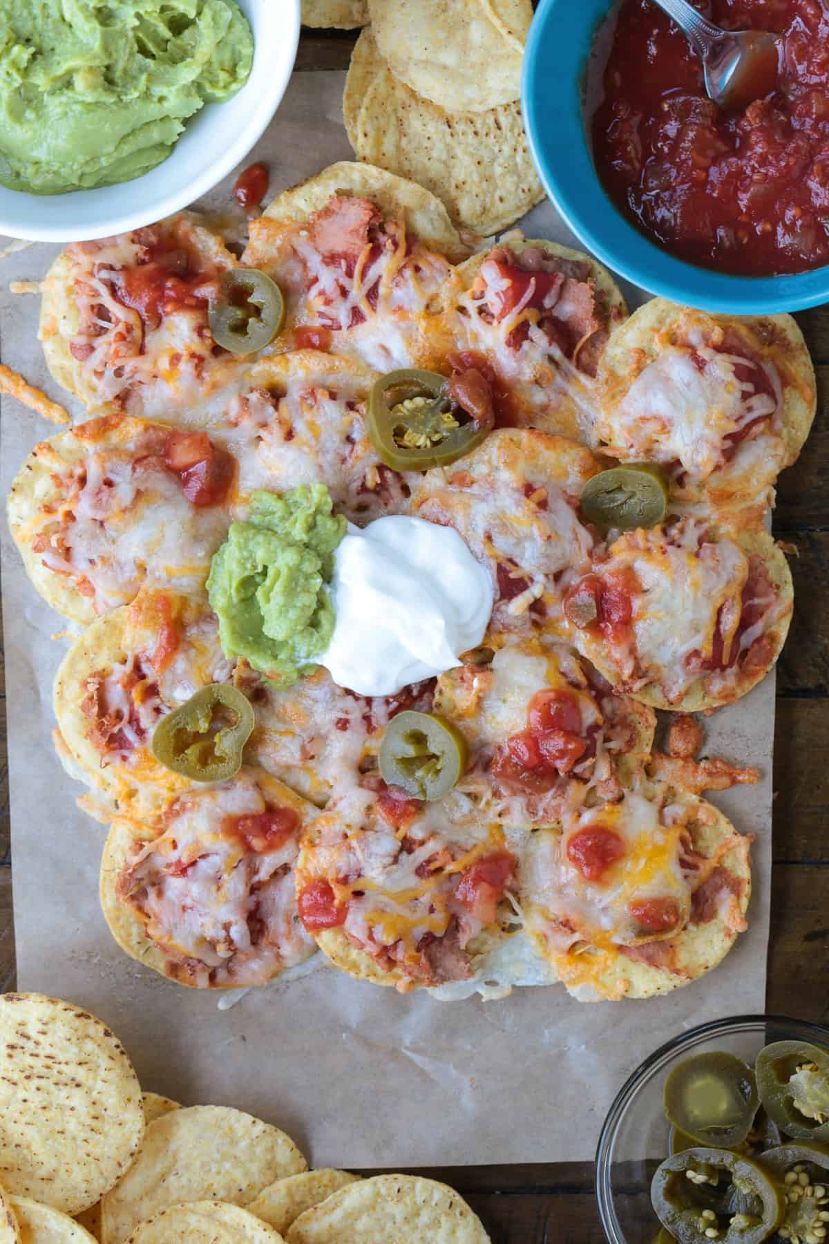 nachos on parchment with toppings on the side