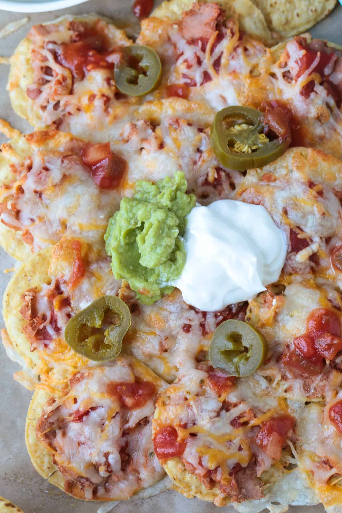 nachos on parchment with guacamole and sour cream