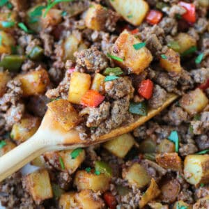 spatula in skillet with scoop of ground beef and potatoes