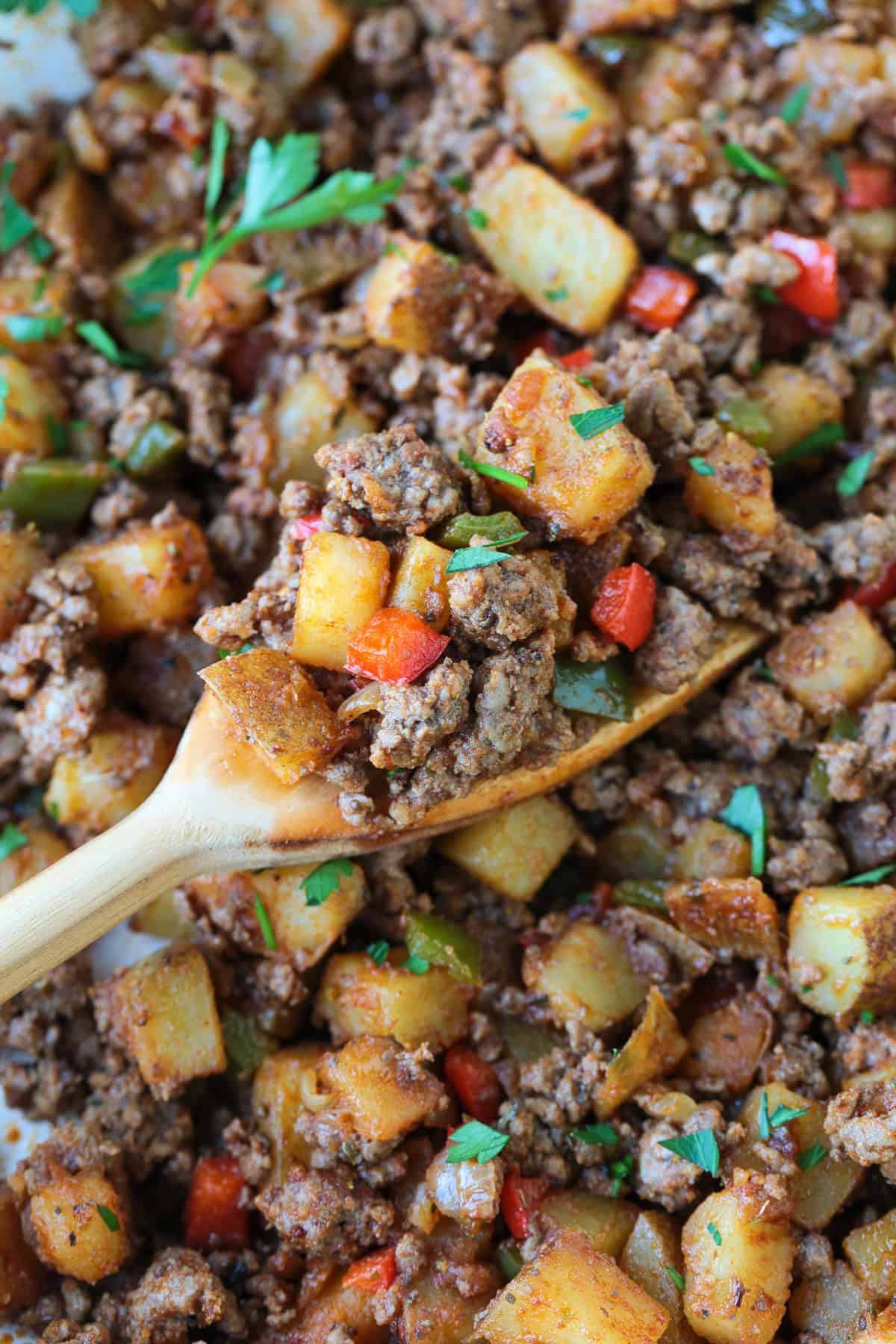 spatula in skillet with scoop of ground beef and potatoes