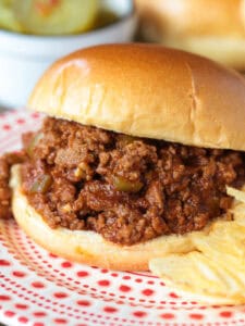 sloppy joe sandwich on a plater with chips and pickles