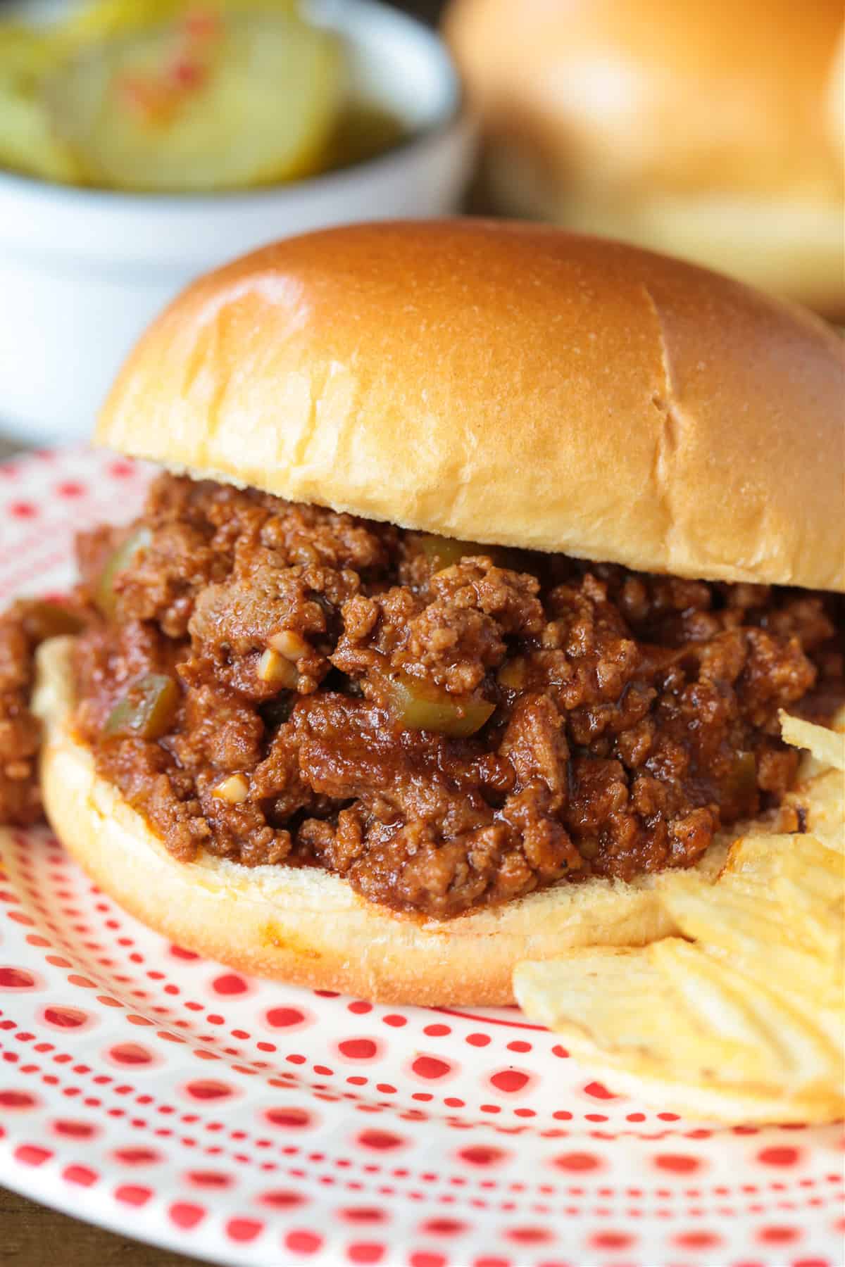 sloppy joe sandwich on a plater with chips and pickles