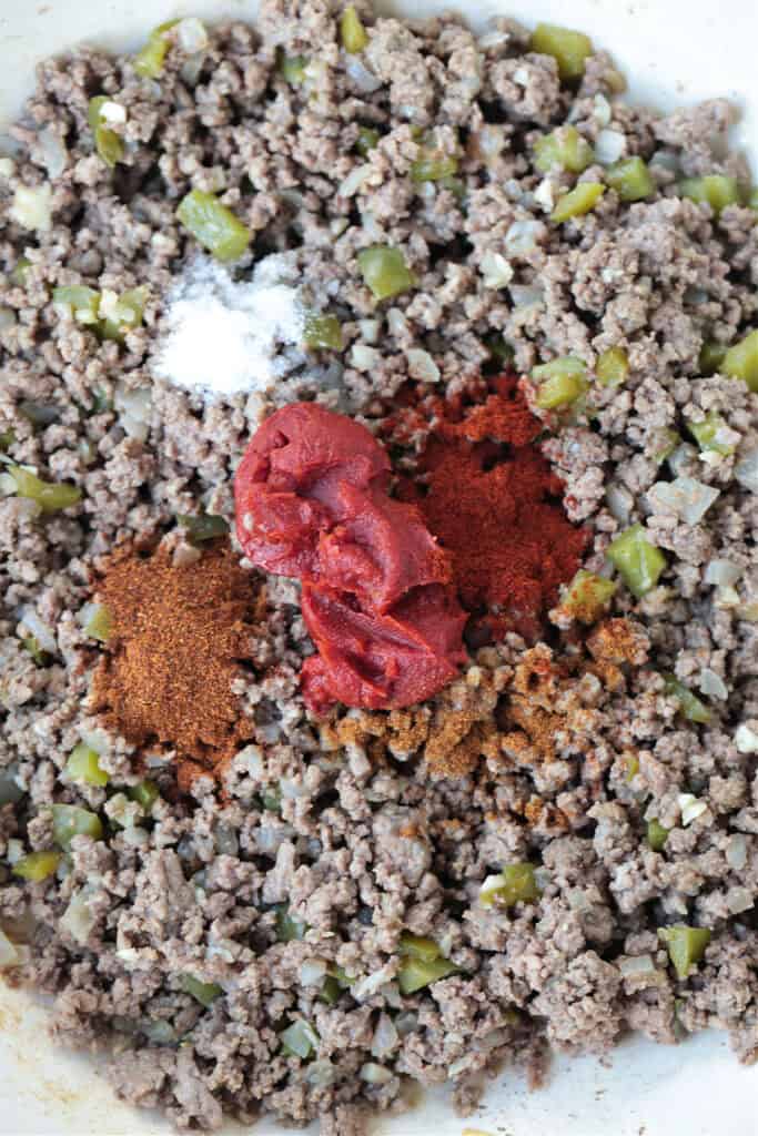 ground beef in a skillet with tomato paste and seasonings