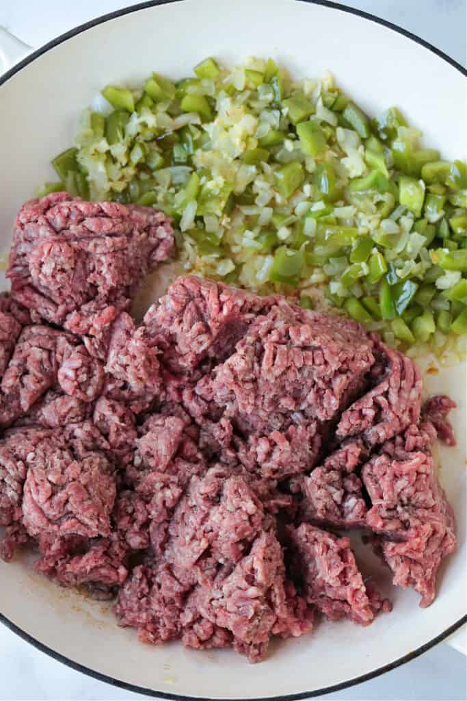 ground beef in a skillet with green peppers and onions