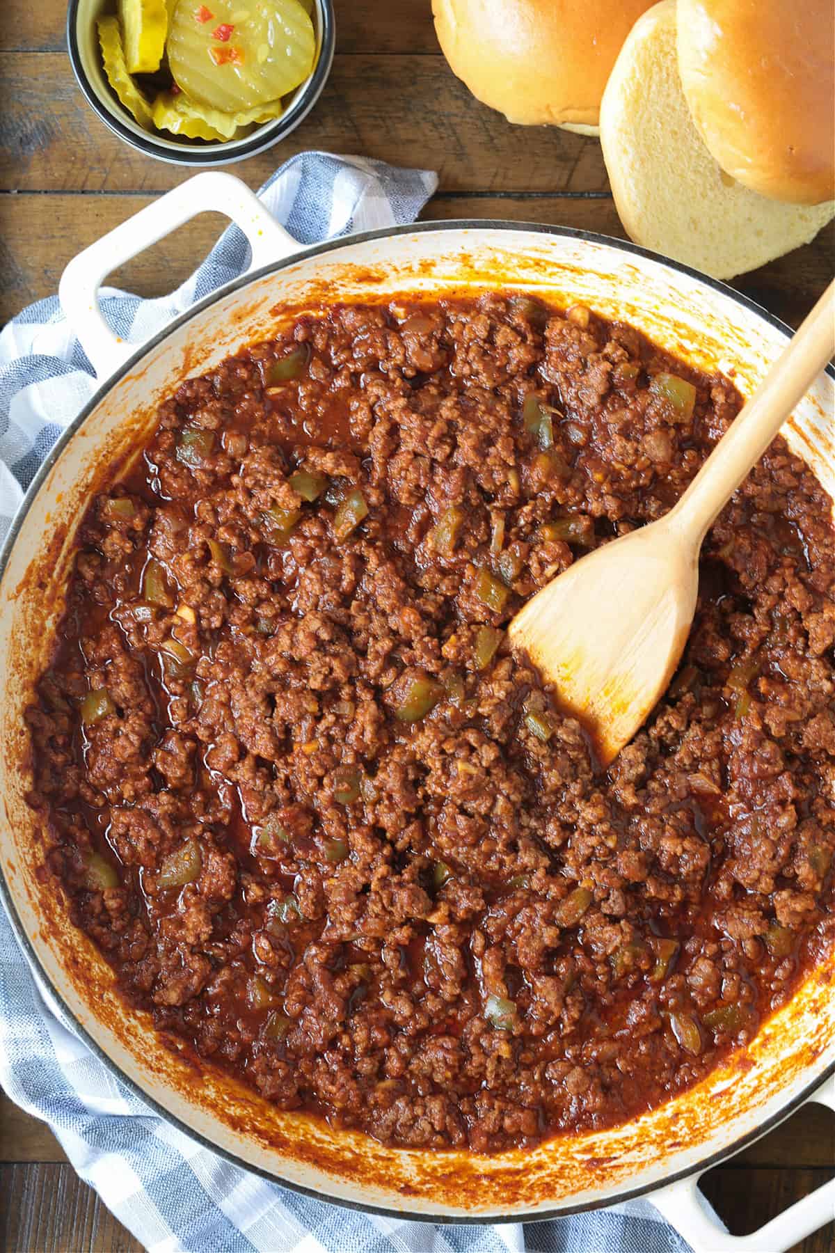 sloppy joes in a skillet from the top with buns and pickles