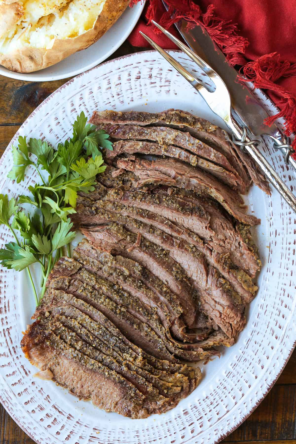 sliced steak on a platter with baked potato