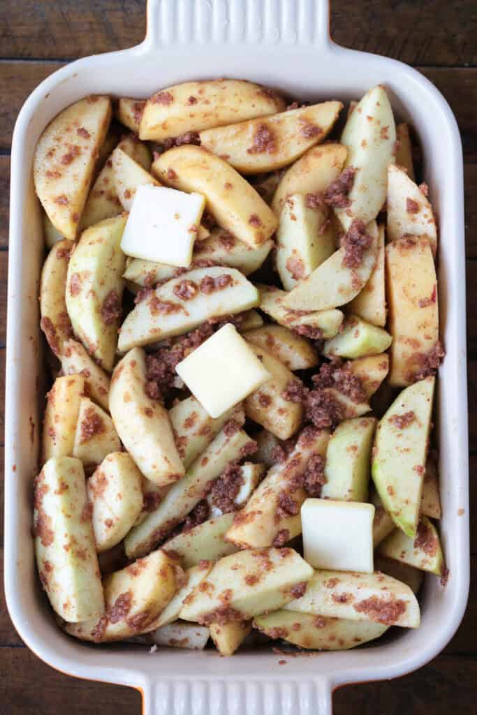 sliced apples tossed in brown sugar and cinnamon in a baking dish