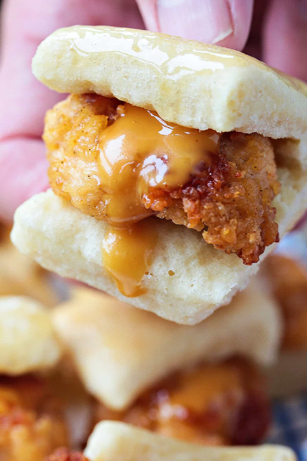 hand holding mini chicken slider with sauce