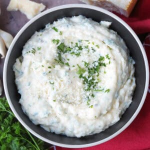 garlic parmesan sauce in black bowl with napkin and parsley