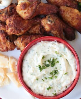 chicken wings on platter with creamy sauce for dipping