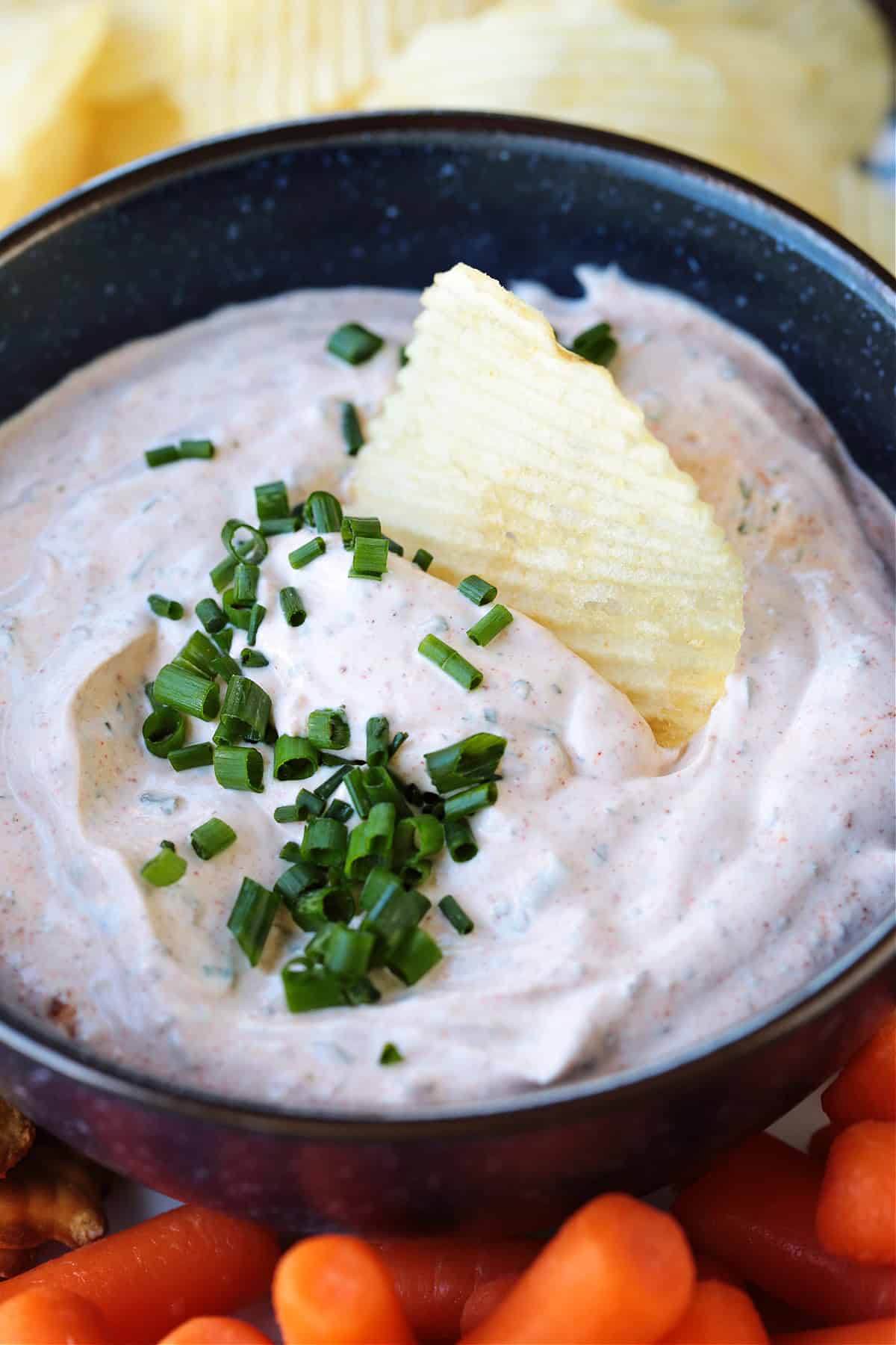 potato chip dipping into bowl of dip