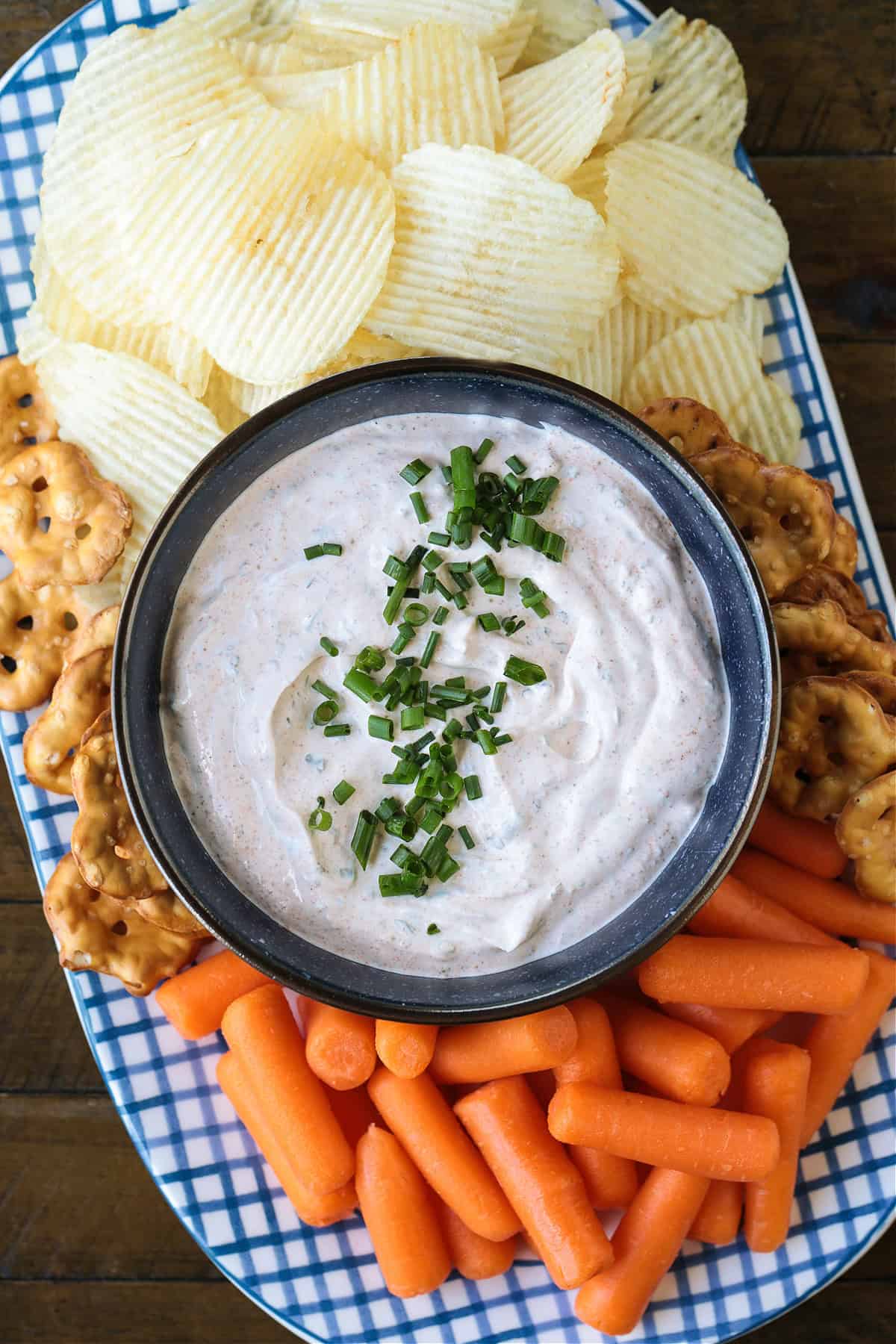 bowl of dip on a platter with chips and carrots